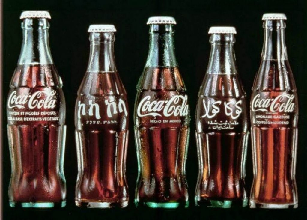 Botellas de Coca-Cola con etiquetas en francés, amárico, español y árabe, manteniendo el mismo rojo y el mismo logotipo